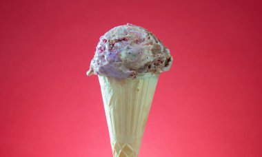 Kırmızı arka planda renkli serpiştirilmiş dondurma külahı. Kapat..