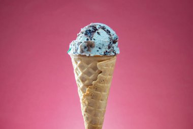 Kırmızı arka planda renkli serpiştirilmiş dondurma külahı. Kapat..