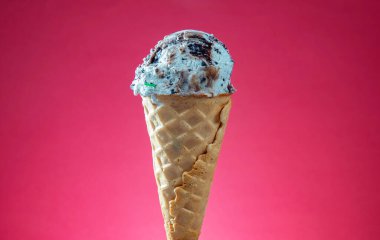 Kırmızı arka planda renkli serpiştirilmiş dondurma külahı. Kapat..