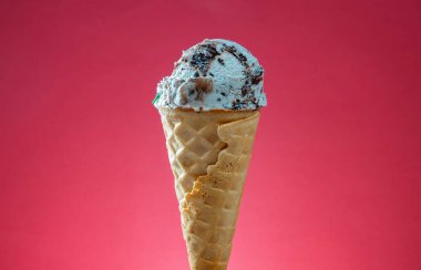 Kırmızı arka planda renkli serpiştirilmiş dondurma külahı. Kapat..