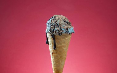 Kırmızı arka planda renkli serpiştirilmiş dondurma külahı. Kapat..