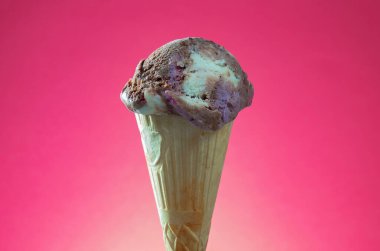 Kırmızı arka planda renkli serpiştirilmiş dondurma külahı. Kapat..