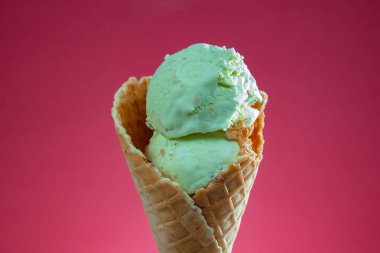 Kırmızı arka planda renkli serpiştirilmiş dondurma külahı. Kapat..