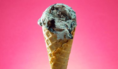 Kırmızı arka planda renkli serpiştirilmiş dondurma külahı. Kapat..