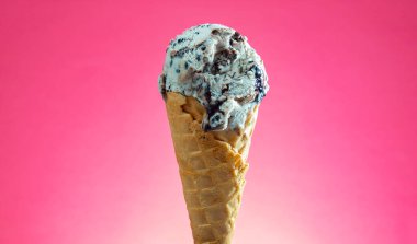 Kırmızı arka planda renkli serpiştirilmiş dondurma külahı. Kapat..