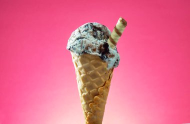 Kırmızı arka planda renkli serpiştirilmiş dondurma külahı. Kapat..