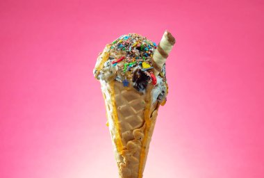 Kırmızı arka planda renkli serpiştirilmiş dondurma külahı. Kapat..