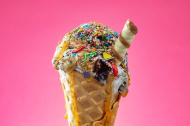 Kırmızı arka planda renkli serpiştirilmiş dondurma külahı. Kapat..