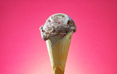 Kırmızı arka planda renkli serpiştirilmiş dondurma külahı. Kapat..