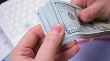 Genç bir finansörün elleri yavaş yavaş para, dolar kaydırıyor. Yavaş çekim.