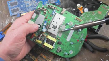 Atölyedeki ana kartı tamir et. Ustanın elleri, kullanım sürecindeki arızalar nedeniyle elektronik aletleri tamir edecek şekilde yakın plan çekimde. Yakın plan. Yavaş çekim.