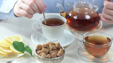 Kahvaltı malzemeleriyle mutfak masasında sıcak çay karıştıran genç bir adam. Yakın plan. Yavaş çekim.