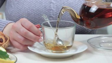 Kaşıkla fincanda çay karıştıran genç bir kız. Yakın plan. Yavaş çekim.