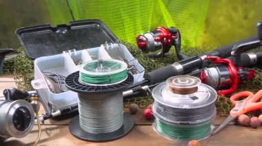 Balık oltası, yavaşça yatay bir düzlemde hareket eden, bir masanın üzerine serilmiş, bir kompozisyonda. Yakın plan. Yavaş çekim.