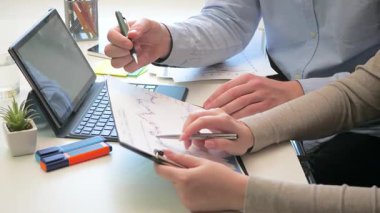 İş adamı ve iş kadını masada yıllık muhasebe raporunda birlikte çalışıyorlar. Erkek ve kadın elleri. Yakın plan. Yavaş çekim.