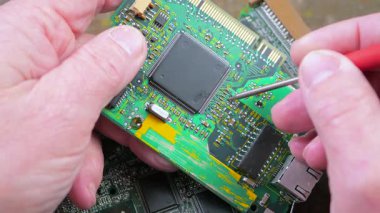 Elektronik tamirci, bilgisayarlar için elektronik panoları tamir eder ve korur. Erkek eli. Yakın plan. Yavaş çekim.