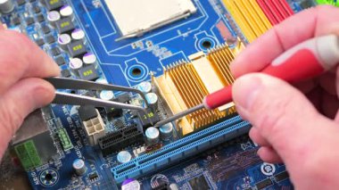 Elektronik tamirci, bilgisayarlar için elektronik panoları tamir eder ve korur. Erkek eli. Yakın plan. Yavaş çekim.