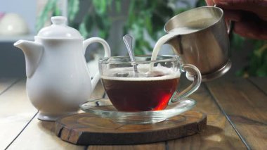 Süt, içmeden önce süt sürahisinden espresso kahvesine dökülür. Erkek eli. Yakın plan. Yavaş çekim.