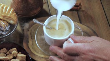 Süt, içmeden önce süt sürahisinden espresso kahvesine dökülür. Erkek eli. Yakın plan. Yavaş çekim.