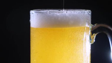 Hafif, köpüklü bira bardağa dökülür. Yavaş çekim.