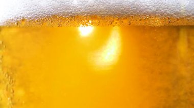 Hafif, köpüklü bira, dolu bir bardakta, dönen, köpüklü hava kabarcıkları. Yakın plan. Yavaş çekim.
