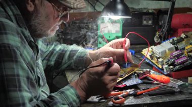 Atölyedeki ana kartı tamir et. Ustanın elleri, kullanım sürecindeki arızalar nedeniyle elektronik aletleri tamir edecek şekilde yakın plan çekimde. Yakın plan. Yavaş çekim.
