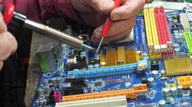 Atölyedeki ana kartı tamir et. Ustanın elleri, kullanım sürecindeki arızalar nedeniyle elektronik aletleri tamir edecek şekilde yakın plan çekimde. Yakın plan. Yavaş çekim.