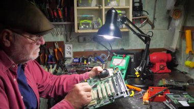 Atölyedeki ana kartı tamir et. Ustanın elleri, kullanım sürecindeki arızalar nedeniyle elektronik aletleri tamir edecek şekilde yakın plan çekimde. Yakın plan. Yavaş çekim.