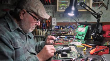 Atölyedeki ana kartı tamir et. Ustanın elleri, kullanım sürecindeki arızalar nedeniyle elektronik aletleri tamir edecek şekilde yakın plan çekimde. Yakın plan. Yavaş çekim.