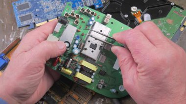 Atölyedeki ana kartı tamir et. Ustanın elleri, kullanım sürecindeki arızalar nedeniyle elektronik aletleri tamir edecek şekilde yakın plan çekimde. Yakın plan. Yavaş çekim.