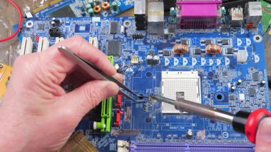 Atölyedeki ana kartı tamir et. Ustanın elleri, kullanım sürecindeki arızalar nedeniyle elektronik aletleri tamir edecek şekilde yakın plan çekimde. Yakın plan. Yavaş çekim.