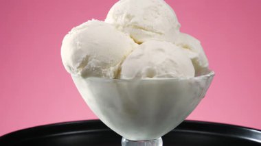 Bardaktaki dondurma, parlak renkli arka planda, yavaşça kendi ekseni etrafında döner..