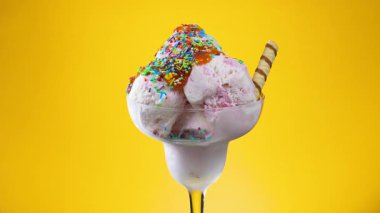 Bardaktaki dondurma, parlak renkli arka planda, yavaşça kendi ekseni etrafında döner..