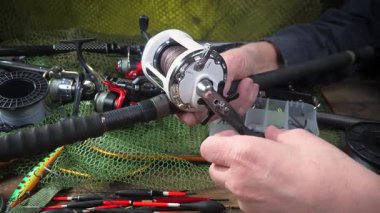 Yaşlı bir balıkçının elleri balıkçılık malzemeleri üretimi ve montajı ile meşguldür..