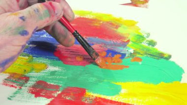 Sanatçının elleri, sanatta yaratıcı imgeler yaratmak için çalışır. Resim boyaları ve fırçalar, palet, guaj ve suluboya kullanarak tuvale çok renkli dokunuşlar uyguluyorlar..