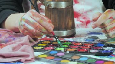 Sanatçının elleri, sanatta yaratıcı imgeler yaratmak için çalışır. Resim boyaları ve fırçalar, palet, guaj ve suluboya kullanarak tuvale çok renkli dokunuşlar uyguluyorlar..