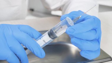 Genç bir doktor şırıngayı inceler, bir hastalığı tedavi etmek için uygulama ve eylem derecesini inceler. Yakın plan. Yavaş çekim.