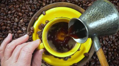 Yaşlı bir adam kahve makinesinden bir fincana sıcak kahve doldurur. Yakın çekim, üst görüş. Yavaş çekim.