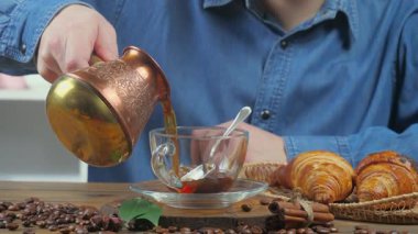 Kot gömlekli genç bir adam kahve makinesinden bir fincana kahve dolduruyor. Yakın plan. Yavaş çekim.