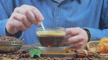 Genç bir adam kahveyi kaşıkla karıştırır. Yakın plan. Yavaş çekim.