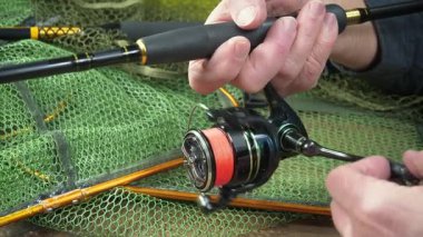 Balıkçı, kurulum ve balıkçı teçhizatı denemeleri ile meşgul. Yakın plan. Yavaş çekim.