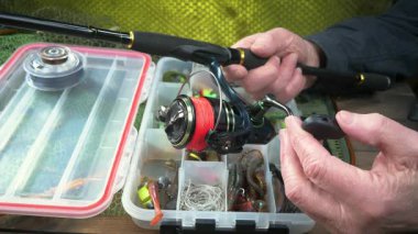 Balıkçı, kurulum ve balıkçı teçhizatı denemeleri ile meşgul. Yakın plan. Yavaş çekim.