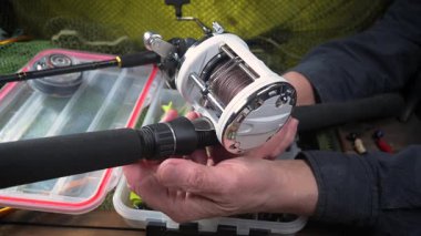 Balıkçı, kurulum ve balıkçı teçhizatı denemeleri ile meşgul. Yakın plan. Yavaş çekim.