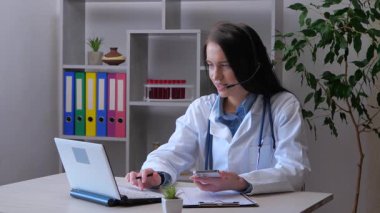 Genç doktor, doktorluk yapıyor, tıbbi ekipmanlarla çalışıyor, hastaların tıbbi geçmişlerini araştırıyor. Yavaş çekim.