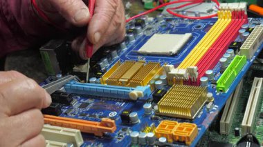 Yaşlı bir zanaatkar bir atölyede elektronik panoları tamir eder. Yavaş çekim.