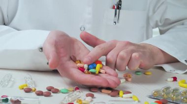 Genç bir doktor tıbbi tabletleri inceler, onları avuçlarının içinde tutar. Yakın plan..