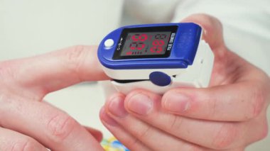 Bir sağlık çalışanı, kan doygunluğunu ölçmek için elektronik bir cihaz taşıyor. Eller, yakın plan. Yavaş çekim.
