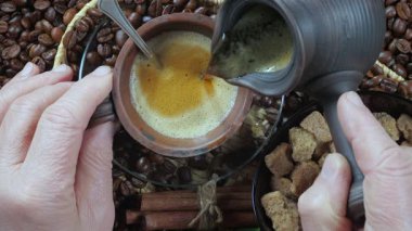 Yaşlı bir adamın elleri kahve makinesinden yavaşça fincana kahve dolduruyor. Yukarıdan bak. Yavaş çekim.