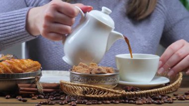 Genç kız kahve fincanından kahve fincanına aromatik espresso koyuyor. Eller, yakın plan. Yavaş çekim.