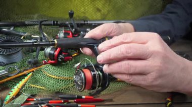 Yaşlı bir balıkçı balıkçı olta takımlarını toplayıp ekipmanları kontrol ediyor. Ellerine yakın çekim..